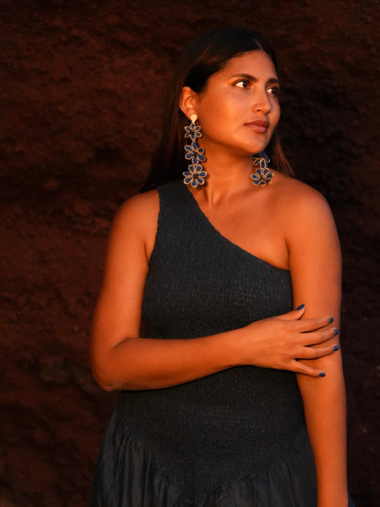 Model wearing the blue Azulita beaded flower earrings by Dearly with a black one-shoulder top