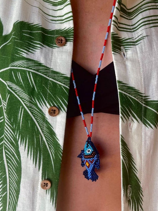 Close-up of the blue beaded fish pendant of the Pez Totem necklace by Pajara Pinta
