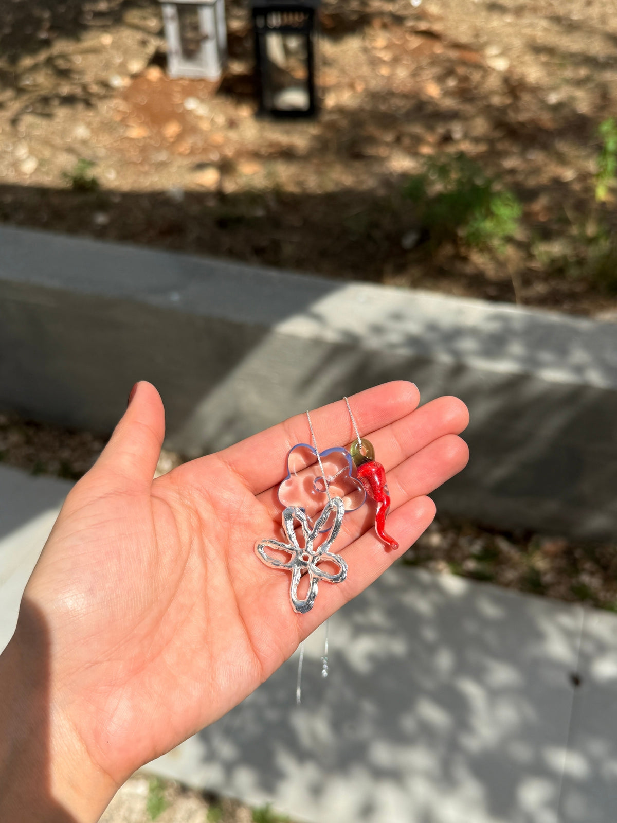 Handmade glass charms of the VOLD Mini Charm Necklace held in a palm