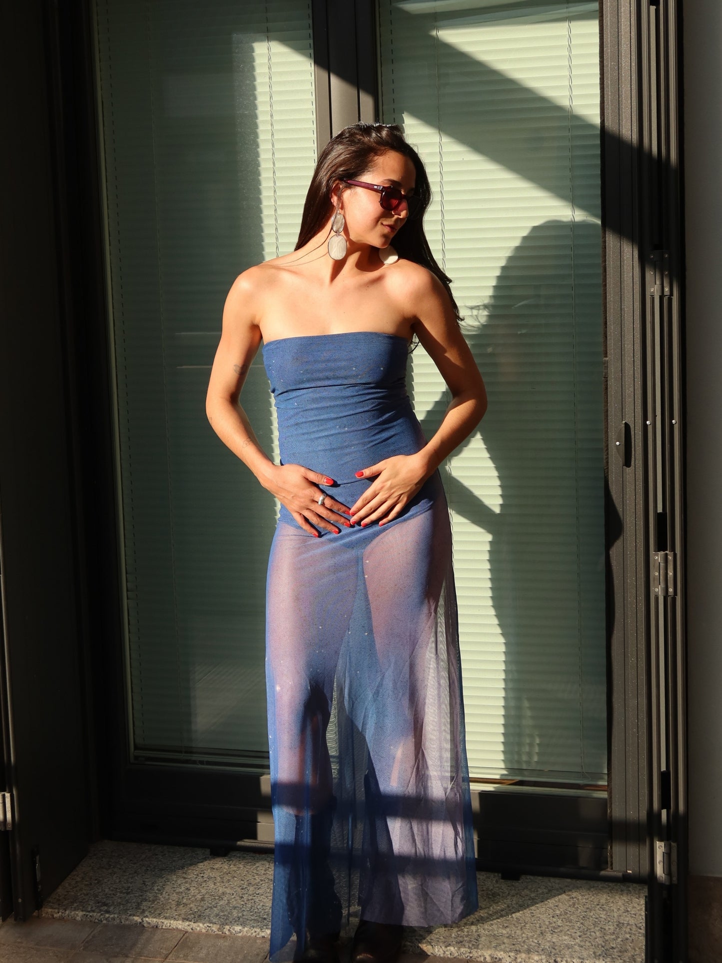 Nocturna Dress by Bahama Mama at a glass door, the mesh sheer from the thigh down