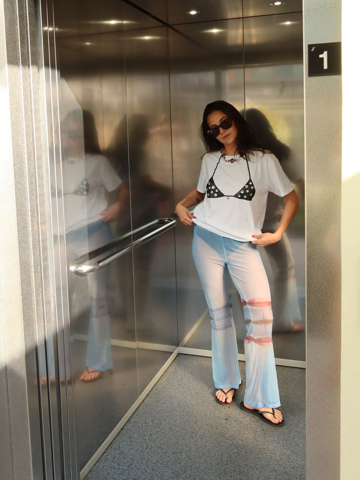 White Surreal T-shirt with the Nacar bikini print, styled with pale blue flared trousers