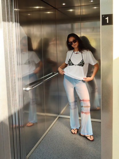 White Surreal T-shirt with the Nacar bikini print, styled with pale blue flared trousers