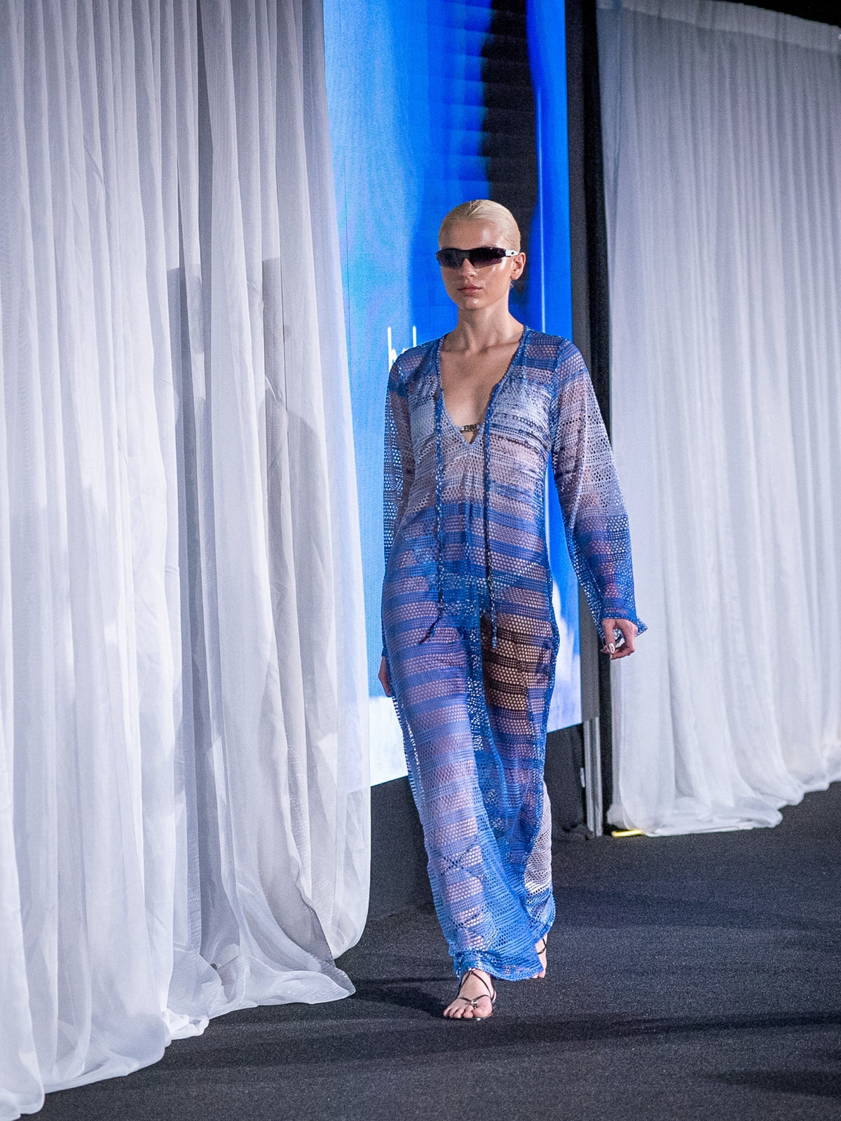 Titipan Cover Up by Bahama Mama walking the runway between white curtains
