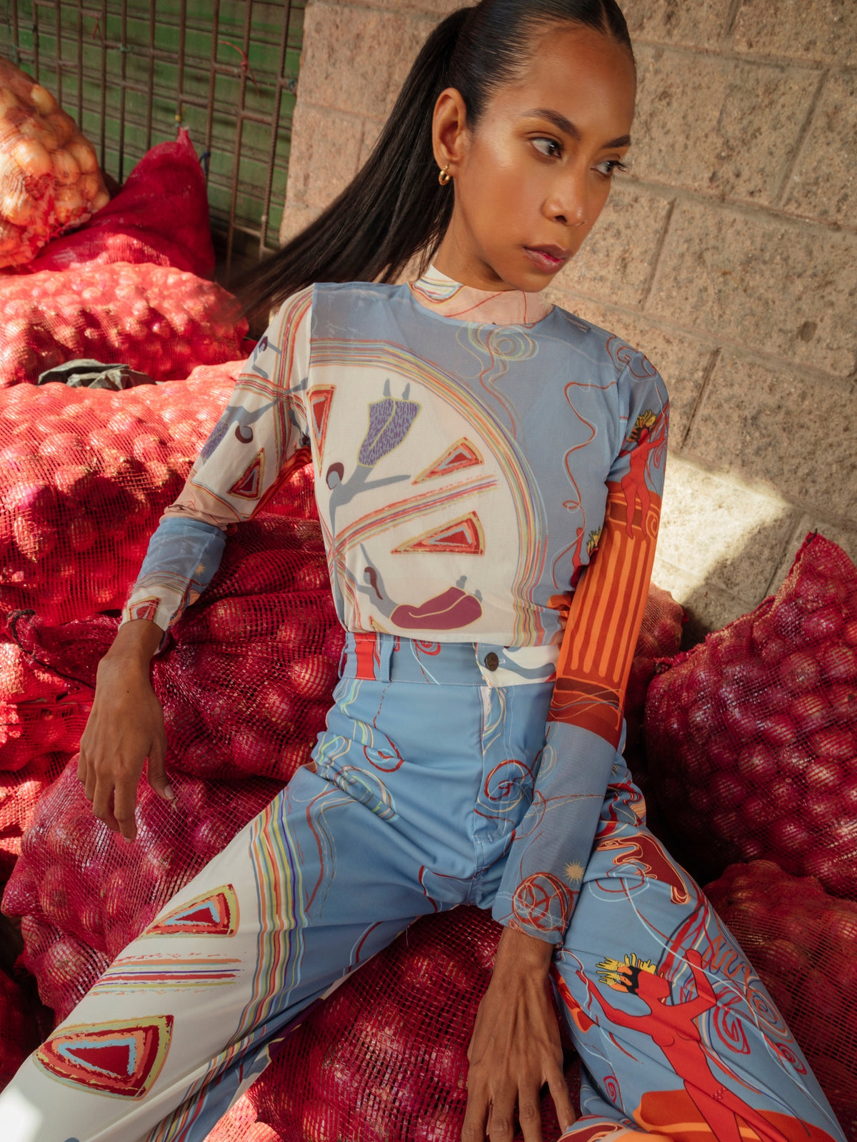 Close view of the Circe Moiras print worn reclining against red market sacks