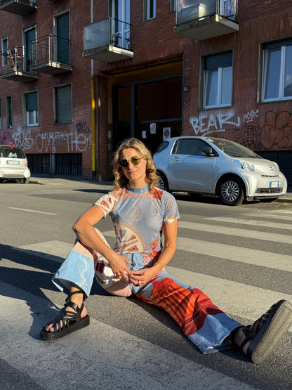 Model in the Circe Moiras printed set seated on a pedestrian crossing in a city street