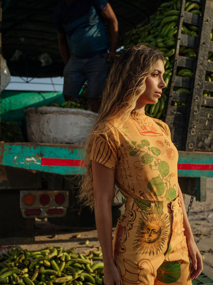 Profile view of the Circe Trofo printed top and trousers beside a banana truck
