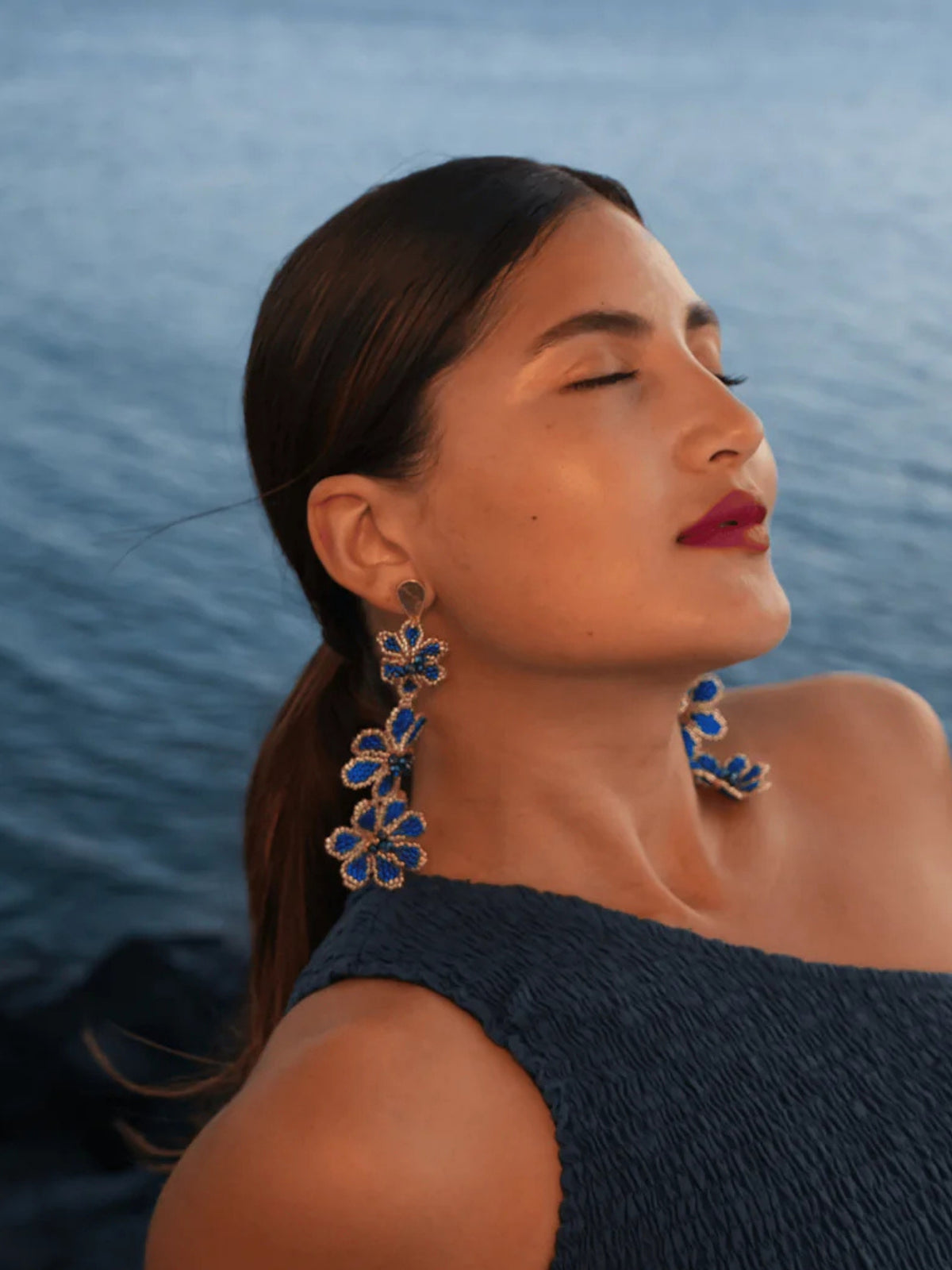 Blue and silver Azulita beaded earrings by Dearly photographed against the sea