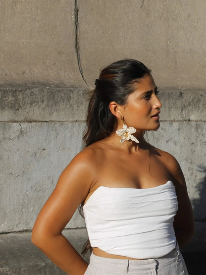 Model wearing the ivory La Flor beaded earrings by Dearly with a white strapless top