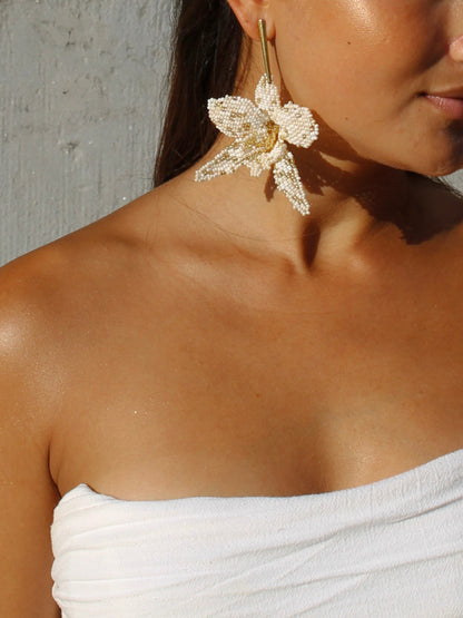 Detail of the ivory and gold La Flor beaded flower earring by Dearly hanging from a slim gold bar