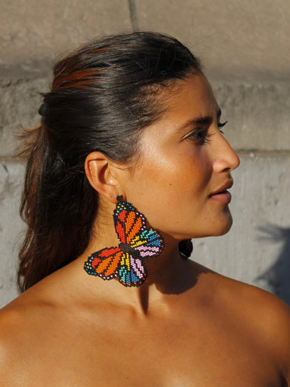 Profile view of the orange and rainbow Mariposa butterfly earring by Dearly