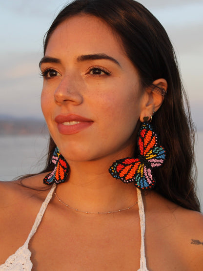 Mariposa beaded butterfly earrings by Dearly worn with a cream crochet top outdoors