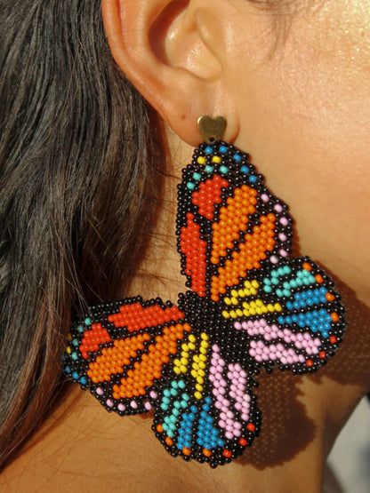 Macro detail of the Mariposa earring by Dearly: monarch wings drawn bead by bead in glass