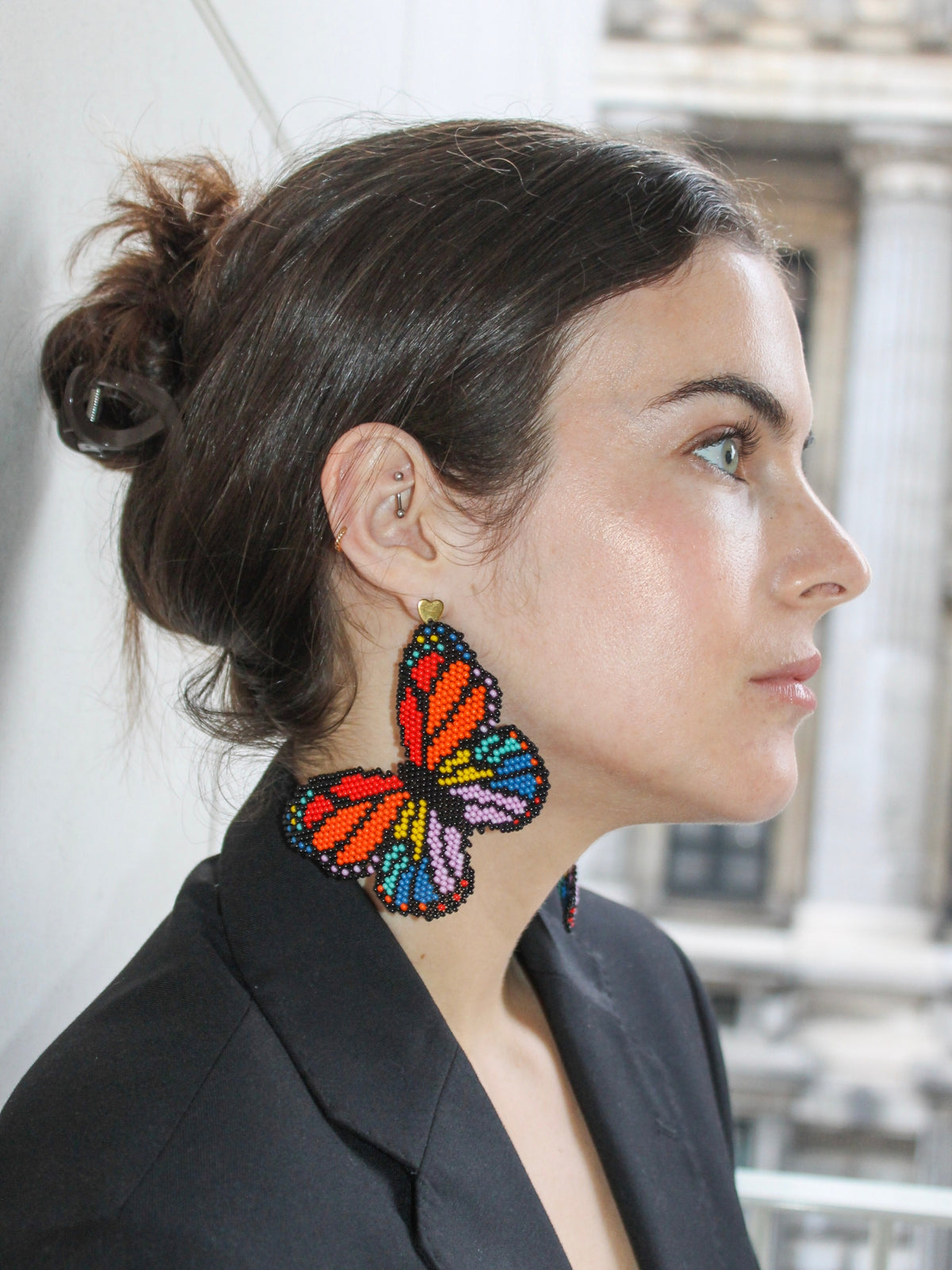 Model in profile wearing the Mariposa butterfly earrings by Dearly with a black blazer