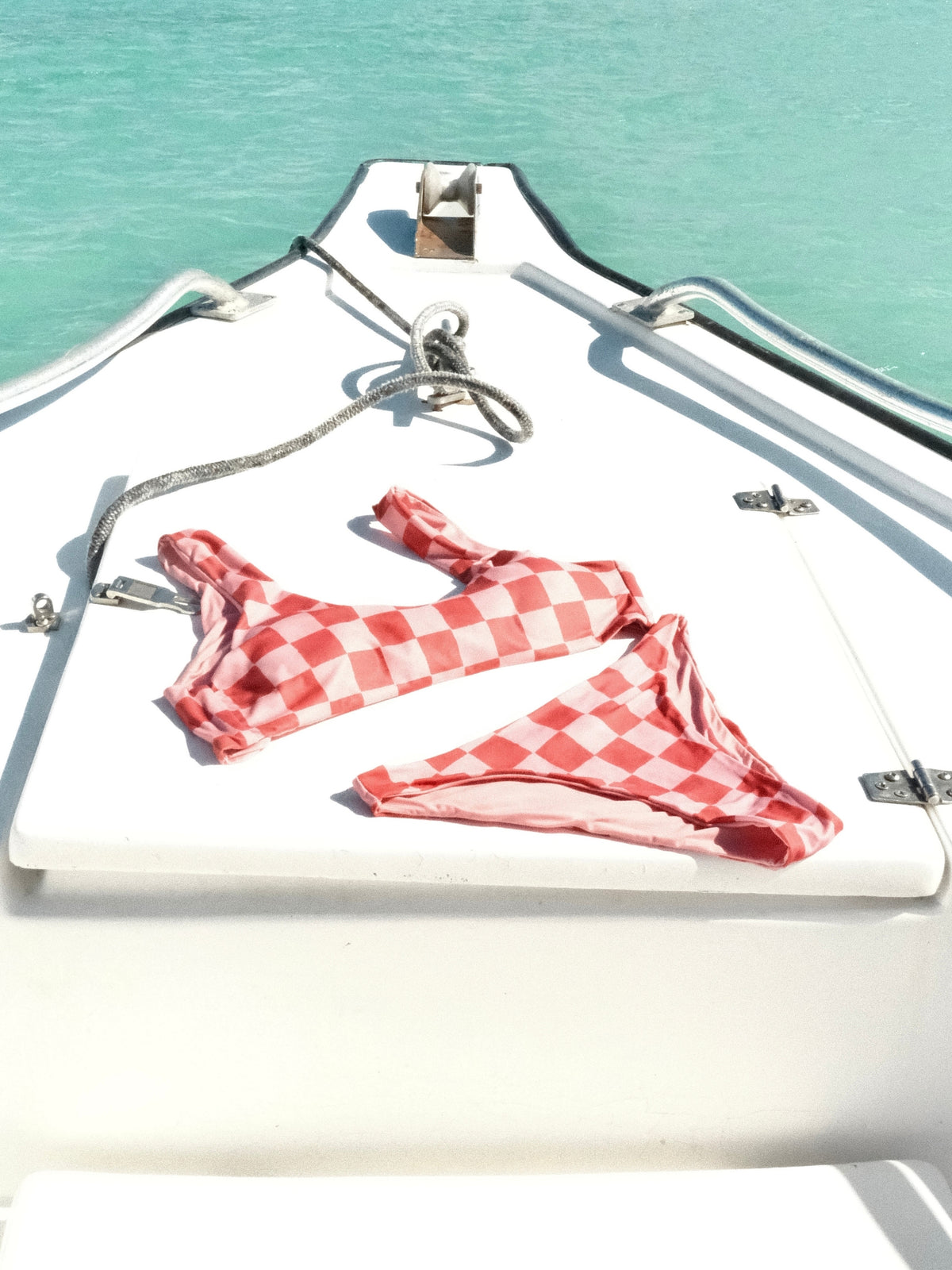 The red checkerboard Lu and Luli bikini by Encantadore laid out on the deck of a boat