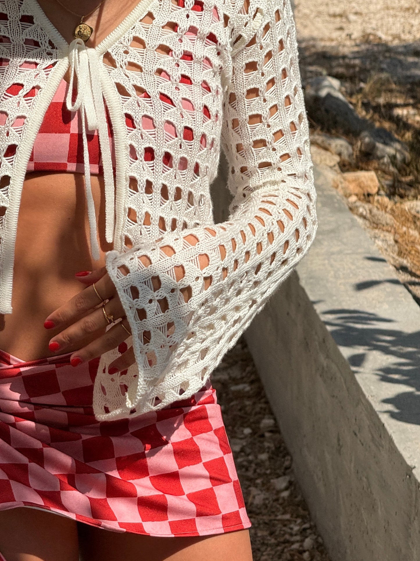 Saskia Red Checkers skirt by Encantadore worn with a white crochet cardigan by the sea