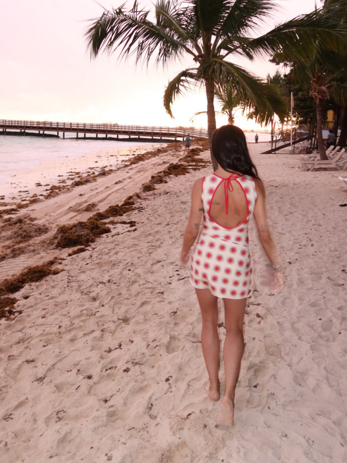 Model walking on the beach at dusk in the Helena Star Red one-piece by Encantadore
