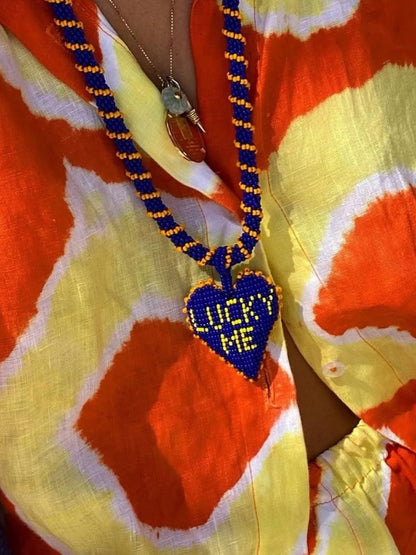 Long Lucky Me necklace by PÁJARA PINTA worn over an orange and yellow tie-dye shirt