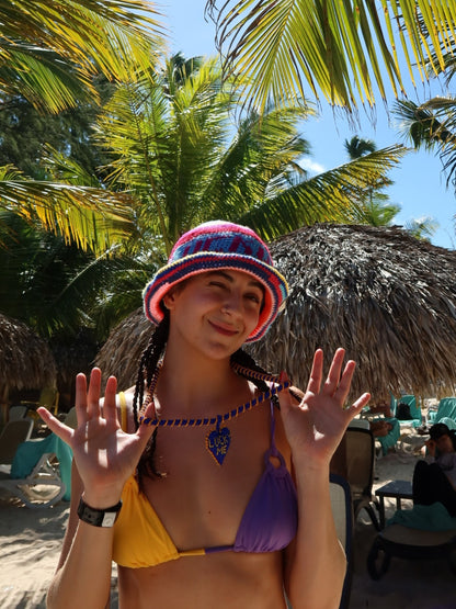 Long Lucky Me beaded necklace by PÁJARA PINTA worn at a beach club with a bucket hat