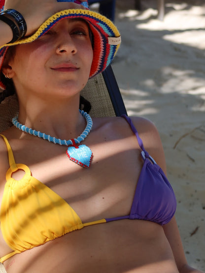 Short Lucky Me necklace by PÁJARA PINTA worn over a yellow and purple bikini at the beach