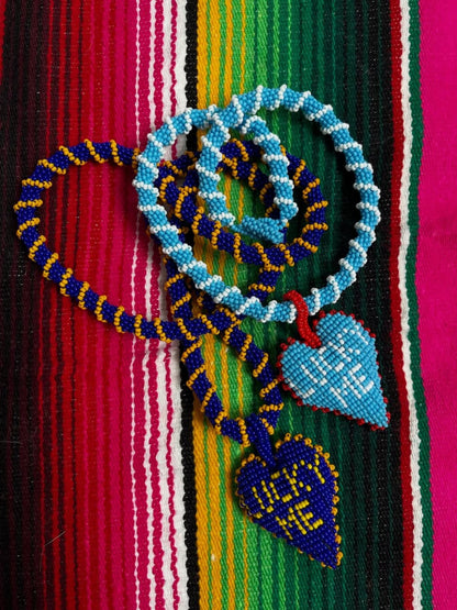 Lucky Me beaded hearts by PÁJARA PINTA laid on a striped woven blanket
