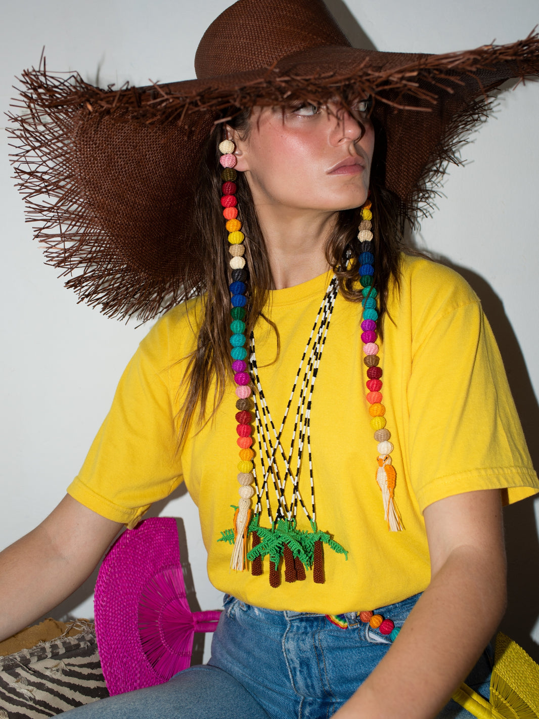 Palma Totem necklace by PÁJARA PINTA worn with a straw hat and a yellow t-shirt