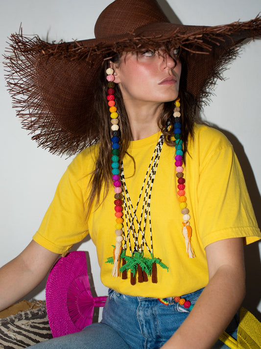 Palma Totem necklace by Pajara Pinta worn with a straw hat and a yellow t-shirt