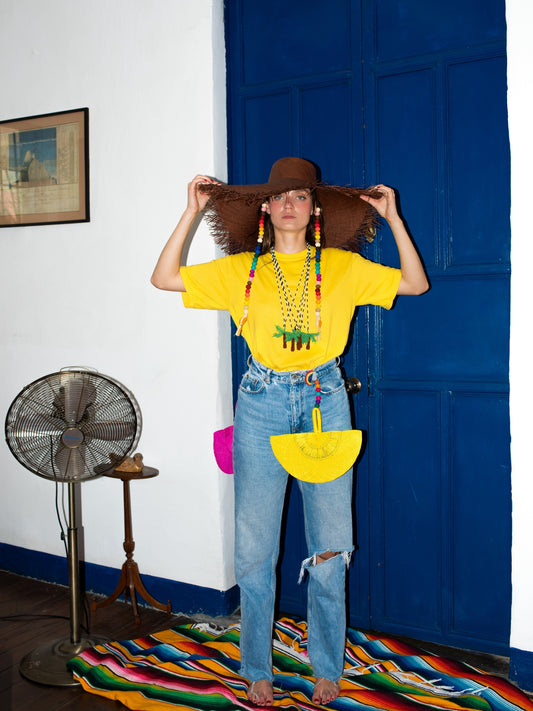 Model wearing several Pajara Pinta beaded totem necklaces with jeans and a yellow tee