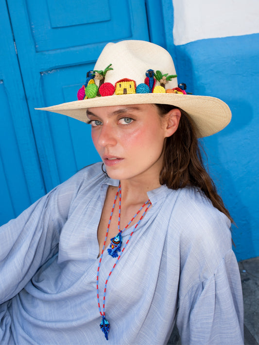 Pez Totem necklace by Pajara Pinta worn with a pale blue kaftan and a decorated straw hat