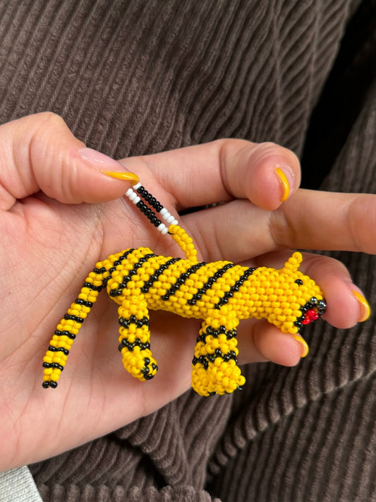Hand holding the yellow beaded tiger pendant of the Tiger Totem necklace by Pajara Pinta