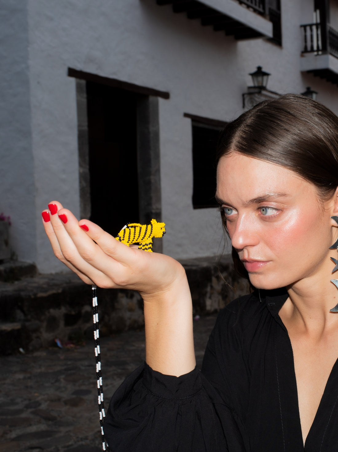 Model holding the yellow beaded tiger of the Tiger Totem necklace by PÁJARA PINTA