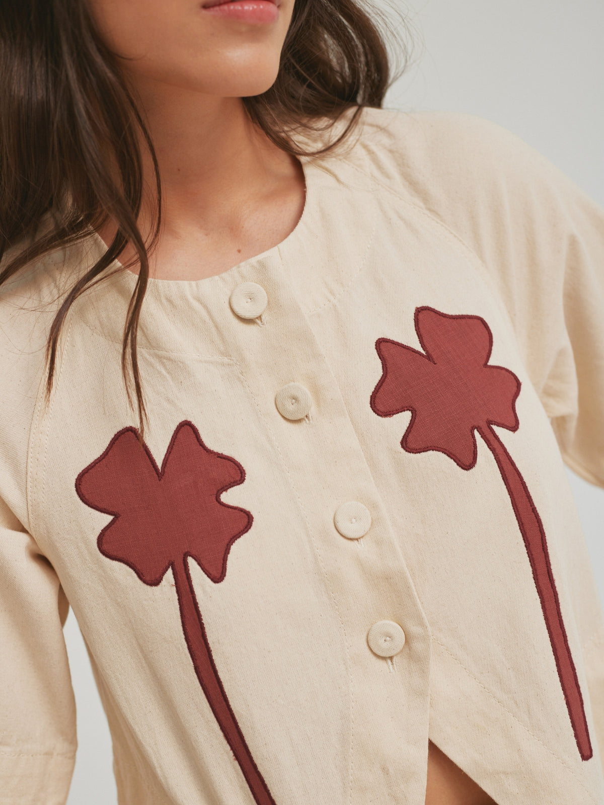 Close view of the red clover appliques and cap buttons on the SIXXTA Clover Fortune Top Red