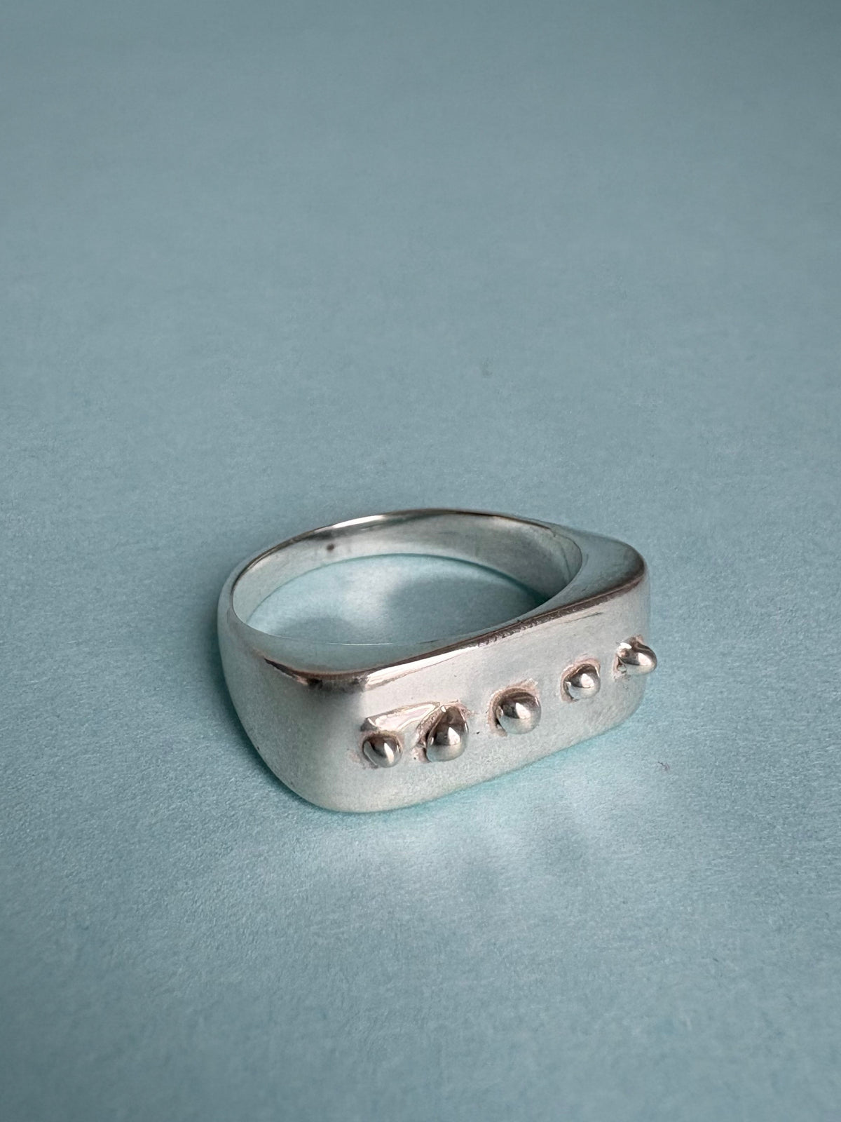 STUDIO MUREA Dot Ring, five silver dots along the flat top, on a pale blue background