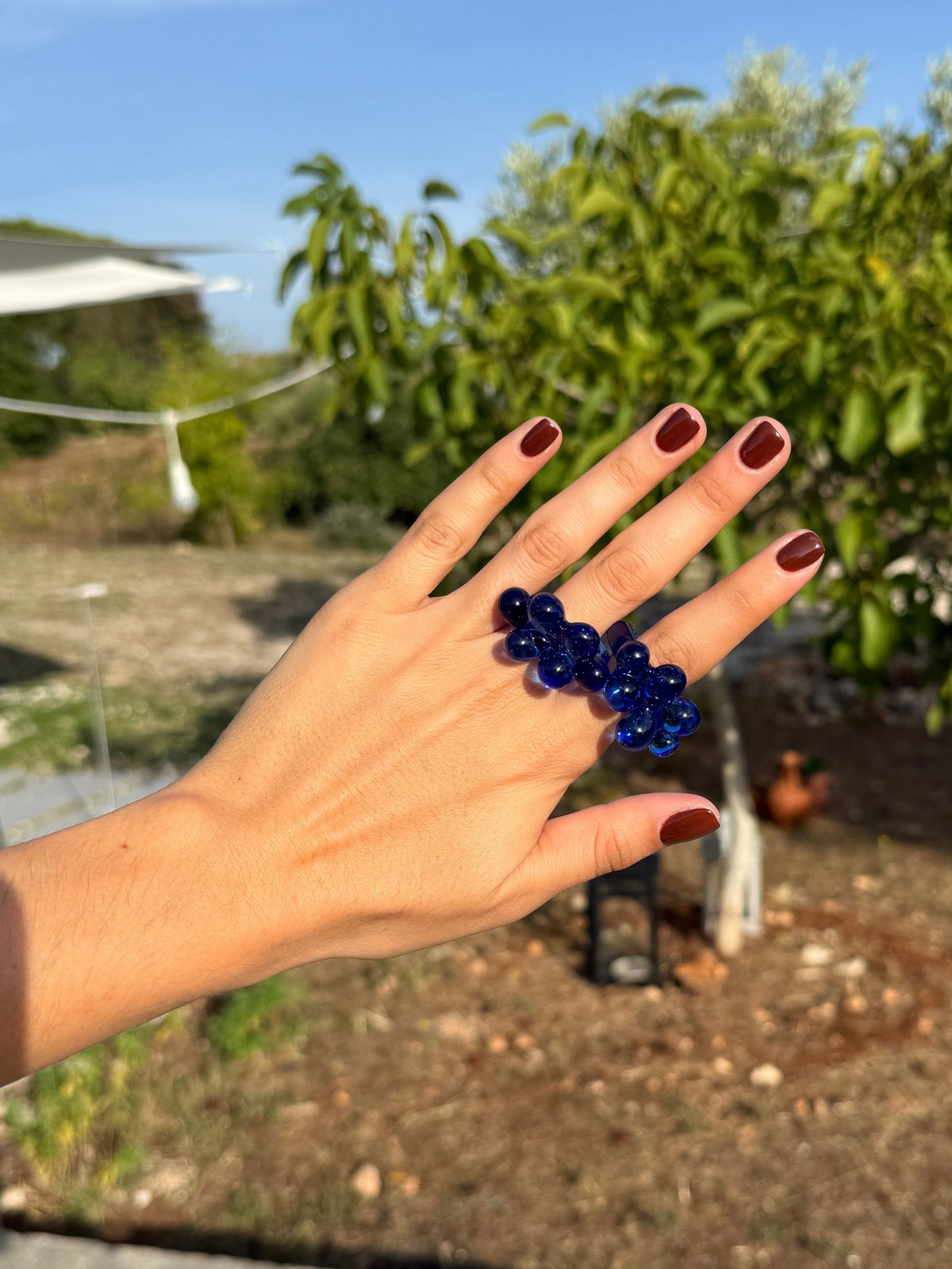 VOLD Bubbles Blue glass ring worn on a hand in a garden