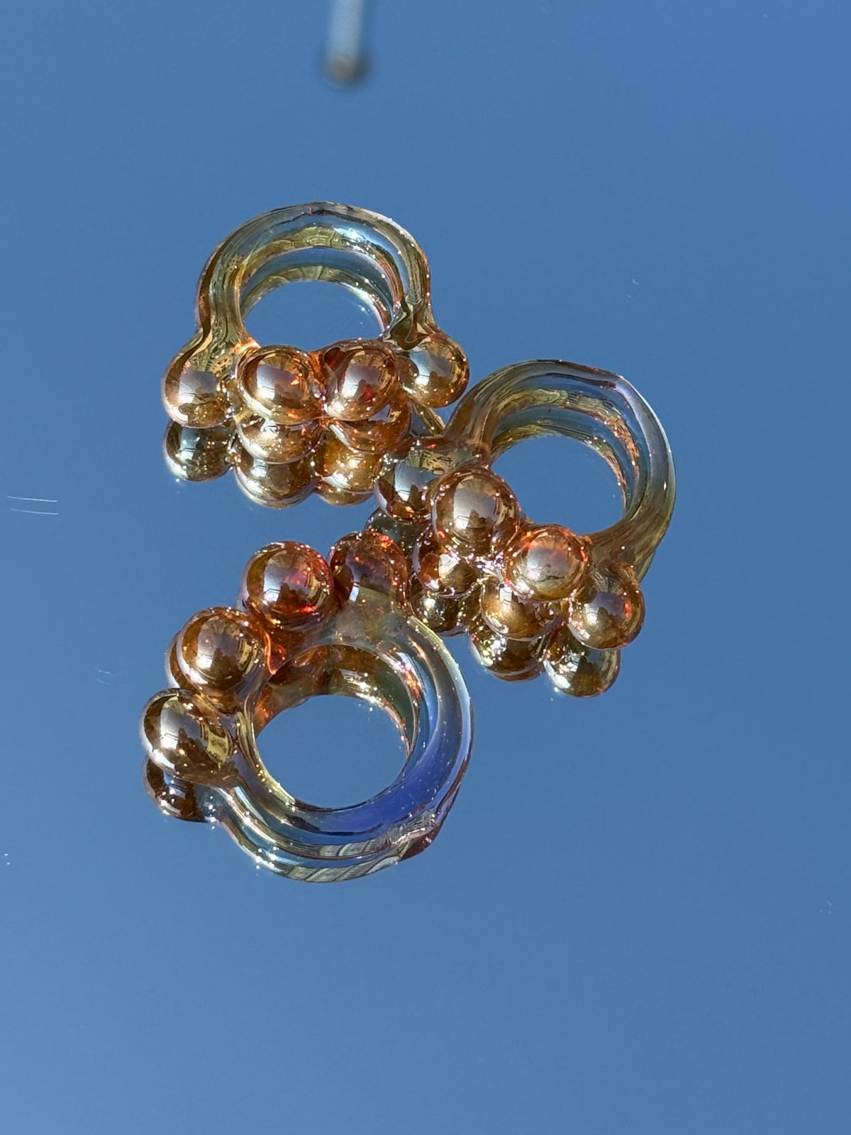The VOLD Bubbles purple glass ring photographed against a blue sky