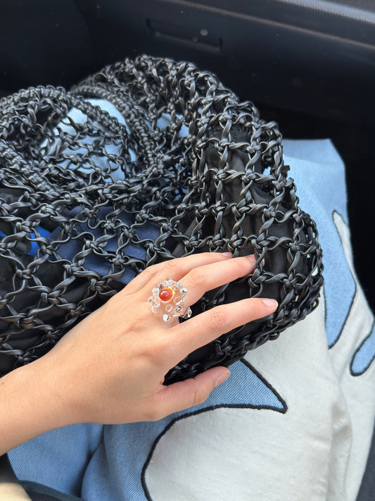 VOLD Donut Ring worn on a hand resting on a black mesh bag