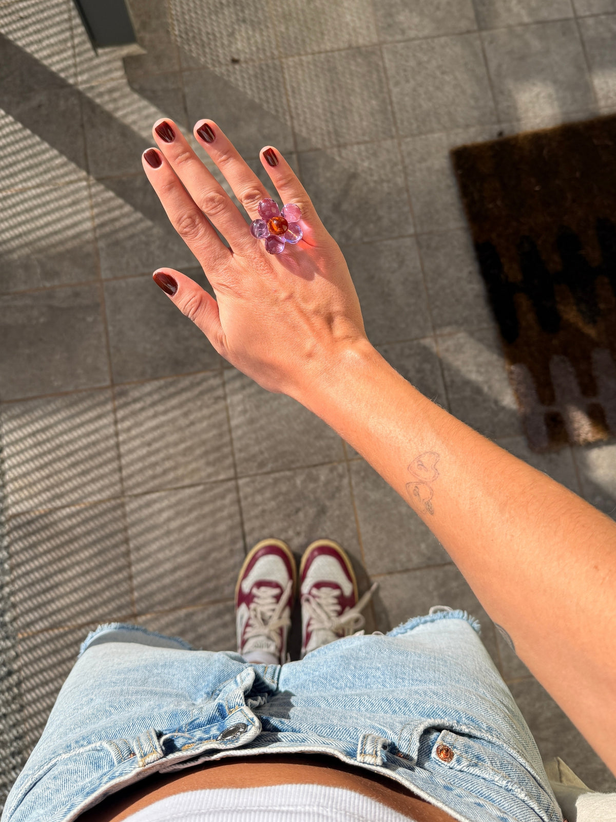 The VOLD Florecita glass ring seen from above with denim shorts