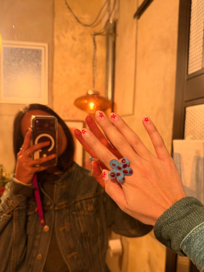 VOLD Paradise Maxi Flower glass ring held up to a mirror